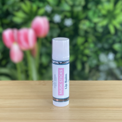 Lip balm stick on a wooden surface with pink tulips in the background